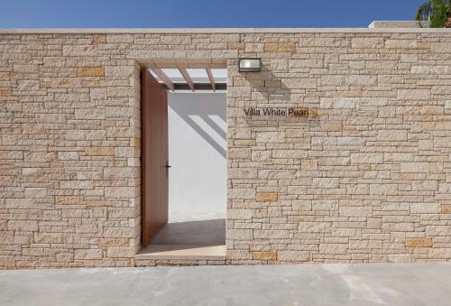 a brick wall with a door with a sign that reads wine white teeth at White Pearl in Paphos City