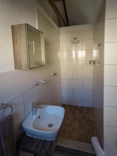 a white bathroom with a sink and a shower at Parkside Guesthouse in Ladismith