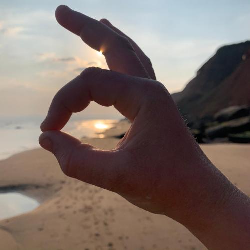 a persons hand making a heart shape at the beach at Sandy feet retreat in Exmouth