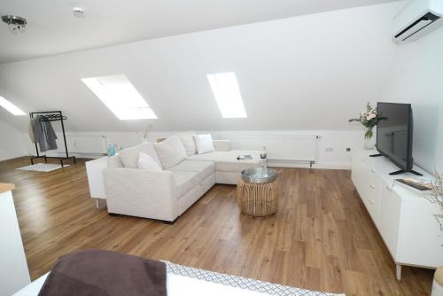 ein Wohnzimmer mit einem weißen Sofa und einem TV in der Unterkunft Ferienwohnungen im HOF68 in Münster