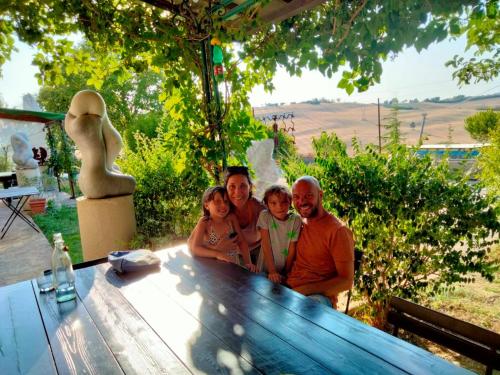a family posing for a picture at a picnic table at "La Casa degli ulivi Art B&B" in Trecastelli