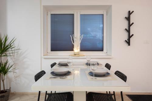 a white dining room table with chairs and a window at APARTMENT SAPICA in Solkan