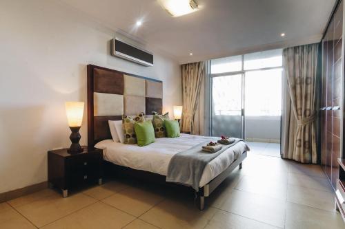 Un dormitorio con una cama grande con almohadas verdes. en 104 Ipanema Beach, en Durban