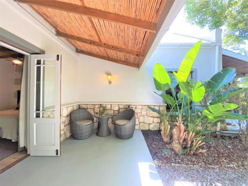 an open door to a patio with chairs and plants at Swellendam Country Lodge - Guest House - B&B in Swellendam