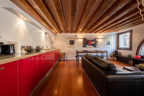 eine Küche mit roten Schränken und einem schwarzen Ledersofa in der Unterkunft Ve.N.I.Ce Cera San Moisè in Venedig