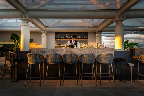 a man standing at a bar with bar stools at Habita79 Hotel Pompeii - MGallery Collection in Pompei