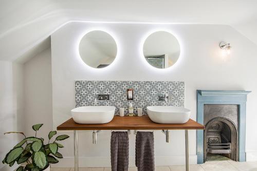 une salle de bain avec deux lavabos sur une table avec deux miroirs dans l'établissement Cusgarne Manor boutique B&B - adults only, à Cusgarne