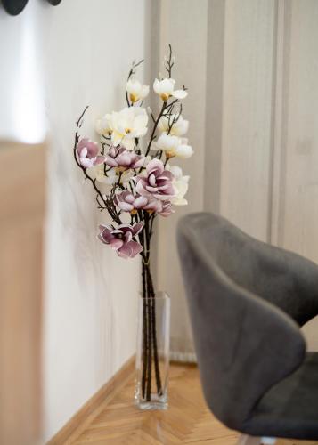 a vase with white and pink flowers on a table at Central Park Home Spa in Arandjelovac