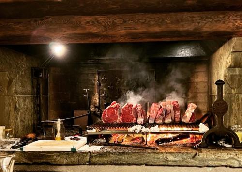 Er wordt vlees gekookt in een open haard. bij A' la Table du Sommelier Chambres d Hôtes & Restaurant in Saint Vincent