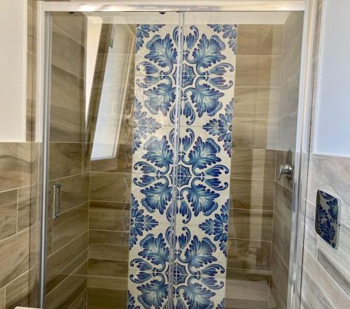 a shower with a blue and white patterned wall at Le case di Fiò in Sciacca