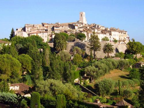 a town on a hill with trees and houses at Appartement Alpes Maritimes in Saint-Paul-de-Vence
