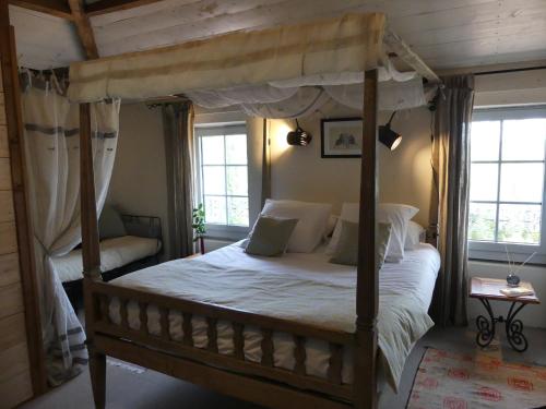 a bedroom with a canopy bed and two windows at Domaine de l’Escuderia in Parentis-en-Born