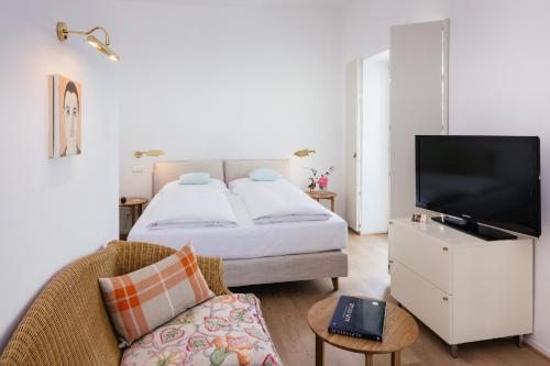 a bedroom with a bed and a tv and a couch at Seehotel Hubertushof in Velden am Wörthersee