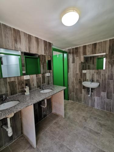 a bathroom with two sinks and a green wall at חאן במדבר ארץ ירוקה in Almog