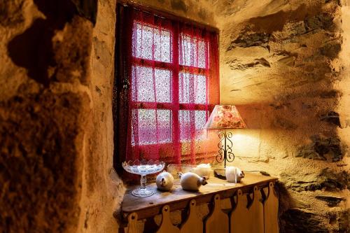 a table with a lamp and a red window at Auberge des Calades in Les Estables