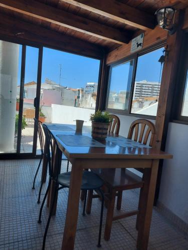 einen Holztisch und Stühle in einem Zimmer mit Fenstern in der Unterkunft Guest House Capitao Mor in Faro