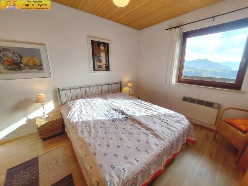 um quarto com uma cama e uma grande janela em Ferienwohnung Montania by FiS - Fun in Styria em Tauplitz