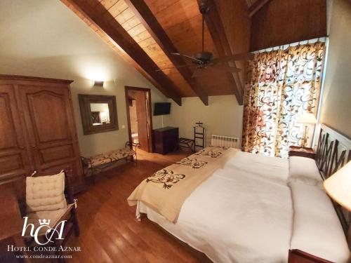 a bedroom with a large white bed and a wooden ceiling at Conde Aznar in Jaca