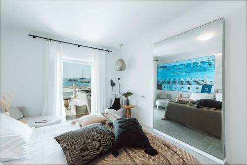 a bedroom with a large mirror on the wall at Mykonos Ammos Hotel - Small Luxury Hotels of the World in Ornos