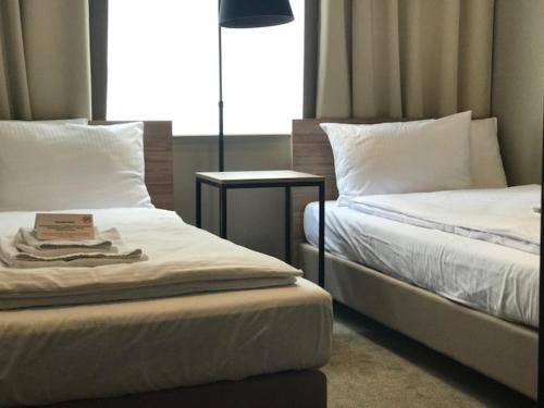 a room with two beds and a table with a lamp at Comm Hotel Poznań Airport in Poznań
