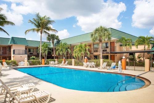 a swimming pool in front of a hotel with palm trees at Super 8 by Wyndham North Palm Beach in North Palm Beach