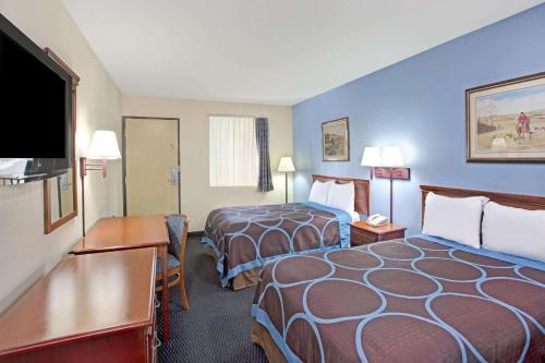 a hotel room with two beds and a flat screen tv at Super 8 by Wyndham Suwanee in Suwanee