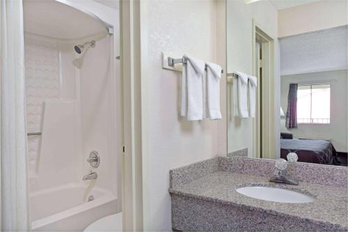 a bathroom with a sink and a tub and a mirror at Super 8 by Wyndham Suwanee in Suwanee