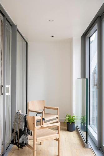 a wooden rocking chair in a room with a window at Cove Landmark Pinnacle in London
