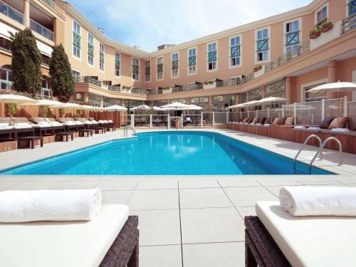 a swimming pool in a hotel with tables and chairs at Grand Hôtel Roi René Aix en Provence Centre - MGallery in Aix-en-Provence