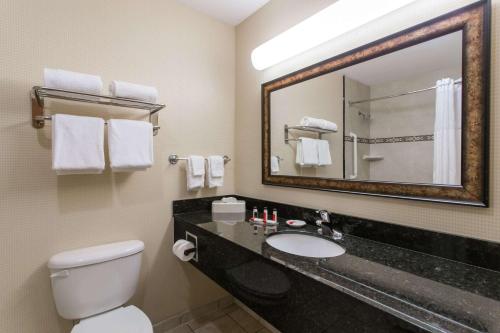a bathroom with a sink and a toilet and a mirror at Days Inn & Suites by Wyndham Fort Pierce I-95 in Fort Pierce