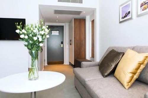 a living room with a couch and a table with flowers at Elite Stadshotellet Eskilstuna in Eskilstuna