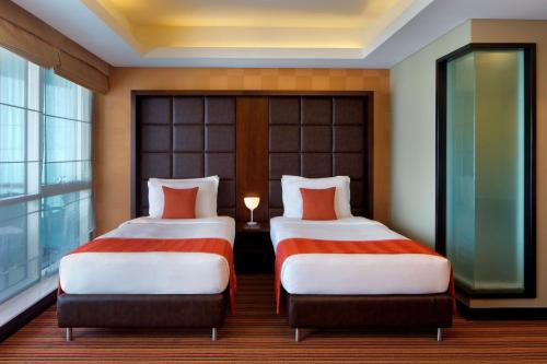 two beds in a hotel room with a window at Radisson Blu Hotel, Dubai Media City in Dubai