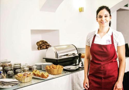 a woman is standing in a kitchen with food at Hotel Solar Dos Mascarenhas in Vila Viçosa