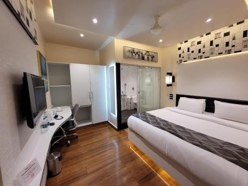 a hotel room with a bed and a desk and a television at Hotel surya dev residency in Bangalore