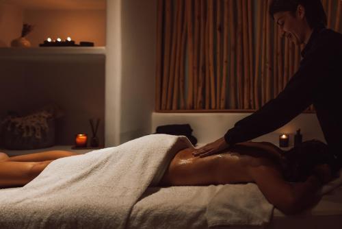 a woman getting a mans back massage in a bed at Mykonos Ammos Hotel - Small Luxury Hotels of the World in Ornos