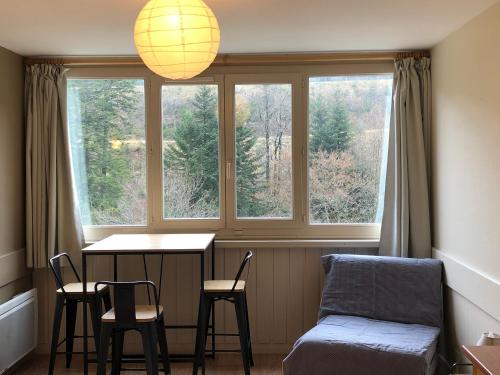 a room with a table and chairs and a window at La Randonnée Résidence Le Bec de L'Aigle in Le Lioran