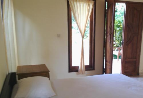 un dormitorio con una cama y una ventana en Gunung Mas Pemuteran, en Pemuteran
