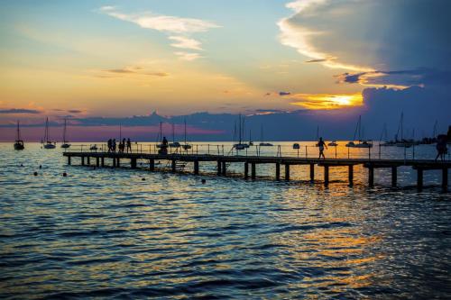 a pier in the water with the sun setting at Debeli Rtič Apartments in Ankaran