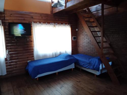 a bedroom with two beds and a ladder and a television at Cabañas Los Teros in San Pedro
