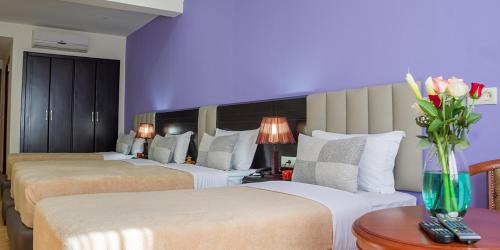a hotel room with three beds and a vase of flowers at Hôtel Suite Martil in Martil