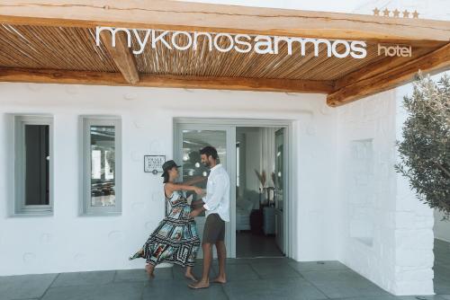 a man and a woman standing outside of a building at Mykonos Ammos Hotel - Small Luxury Hotels of the World in Ornos