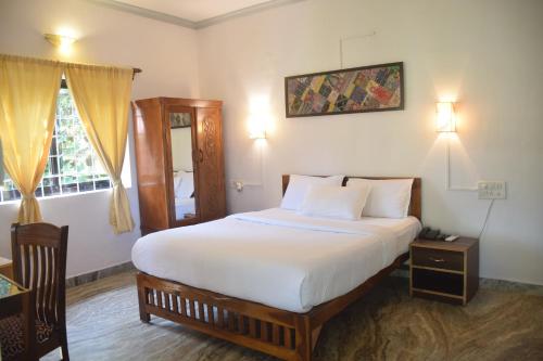 1 dormitorio con 1 cama grande con sábanas blancas en Laliguras Villa 200 Mts from candolim beach, en Candolim