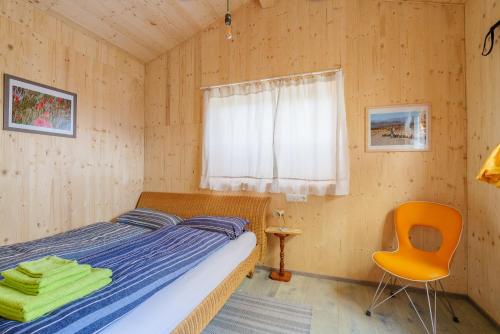 a bedroom with a bed and a chair and a window at Tiny-Ferienhäusle Casa Wendy in Loßburg