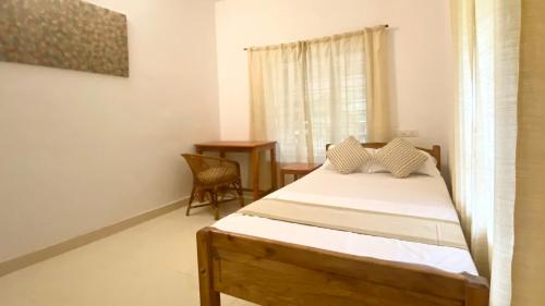 a bedroom with a bed and a table and a window at Tattwamasi Ayuryoga with Breakfast and Yoga in Varkala
