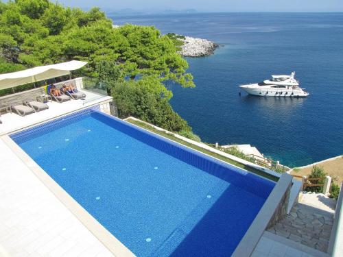 een blauw zwembad met een boot in het water bij Villa Mirosa in Saplunara