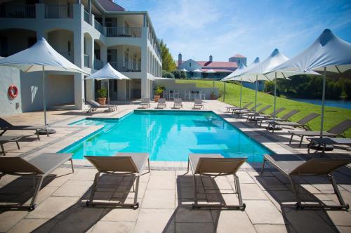 einen Pool mit Stühlen und Sonnenschirmen neben einem Gebäude in der Unterkunft Asara Wine Estate & Hotel in Stellenbosch