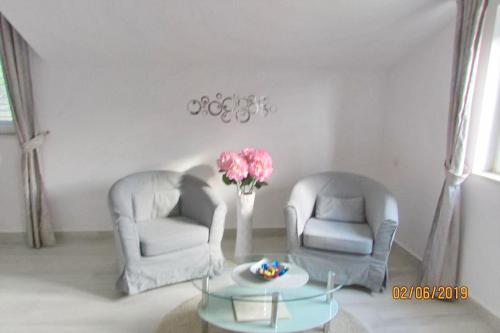 two chairs and a table with a vase of flowers in a room at Villa Mirosa in Saplunara