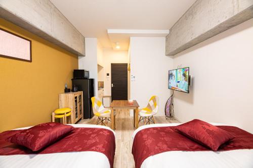 a bedroom with two beds and a table and chairs at STAYTUS - Vacation STAY 62189v in Kagoshima