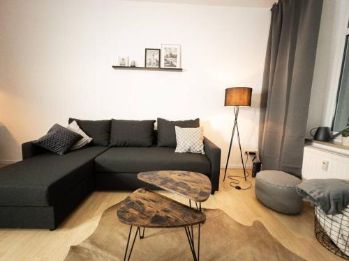 a living room with a black couch and a table at Purer Luxus mit 2 Schlafzimmern, Balkon und Privat-Parkplatz in Leipzig