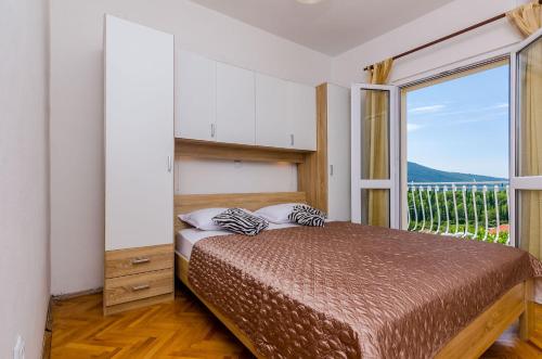 a bedroom with a bed and a large window at Villa Dalmatian Gem in Gruda